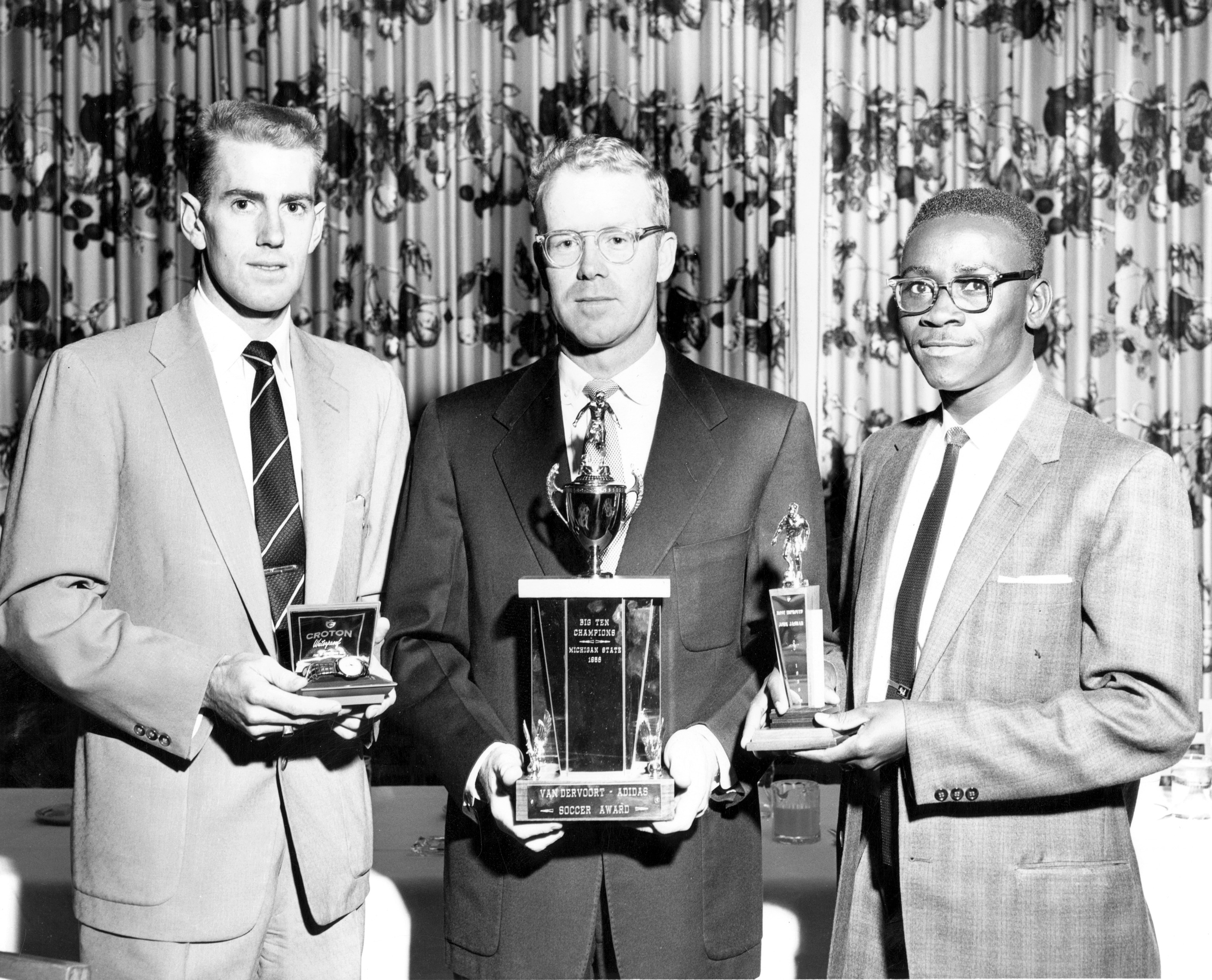 Three men hold trophies and prizes from Big Ten Soccer Championship Three men hold trophies and prizes from Big Ten Soccer Championship